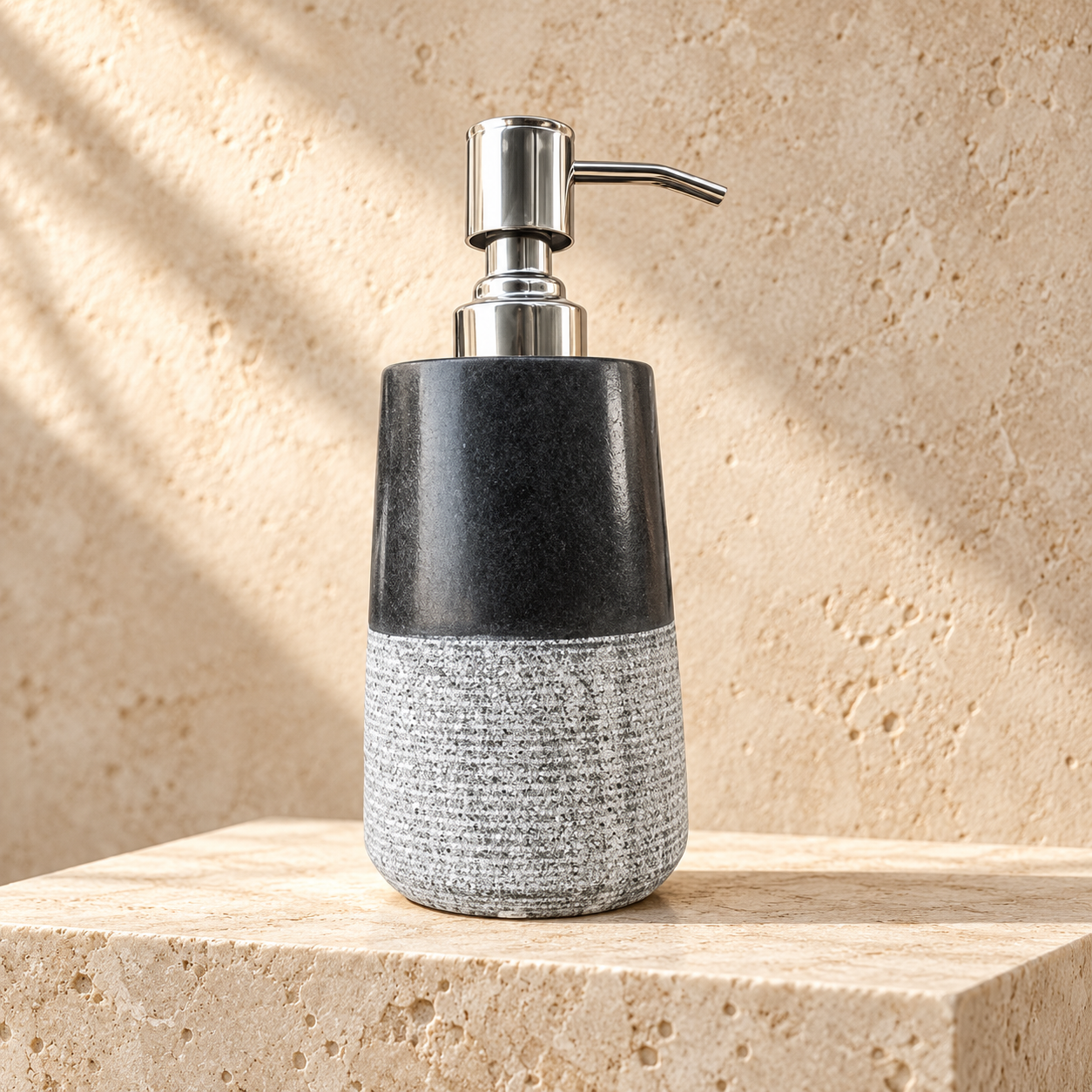 Black marble soap dispenser with polished metal pump on a warm stone surface